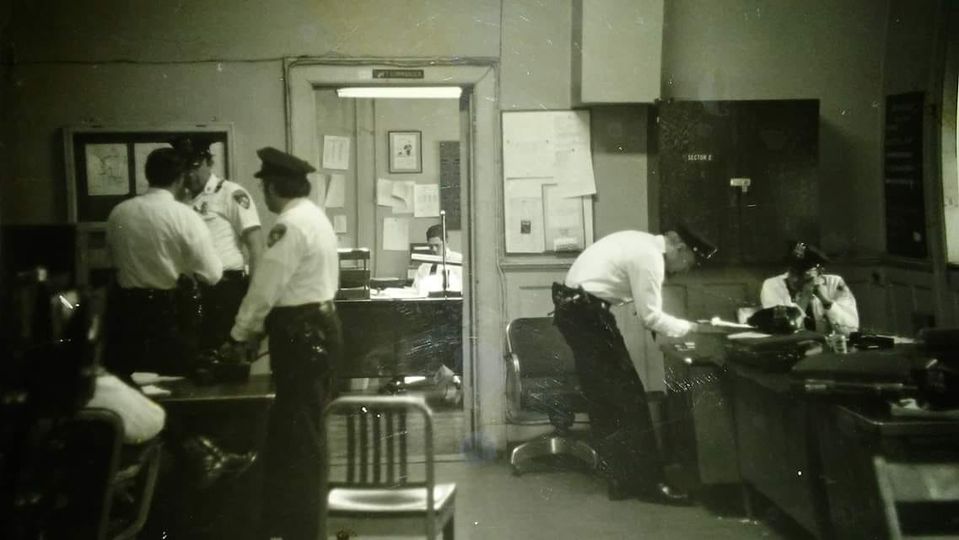 This photo was taken in the old Central District HQ building Sunday morning change over day. Sitting at the desk on the right was OIC Bobby Costin with Bill standing at the desk. Officer standing behind him is his partner, Paul Steimetz. The officer sitting at the desk in the background is Sgt Clemments, who was shot and killed by his ex wife